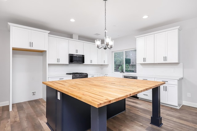 kitchen featuring white cabinets, an inviting chandelier, gas stove, a kitchen island, and pendant lighting