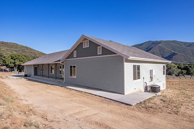 rear view of house with a patio, central air condition unit, and a mountain view