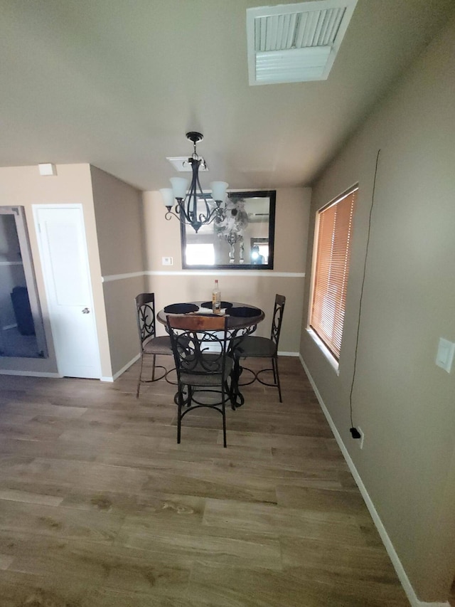 dining area featuring wood-type flooring and a chandelier