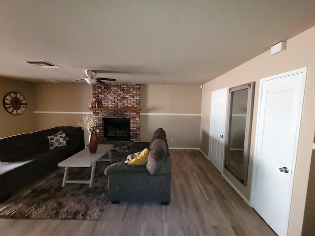 living room featuring hardwood / wood-style flooring, a brick fireplace, and ceiling fan