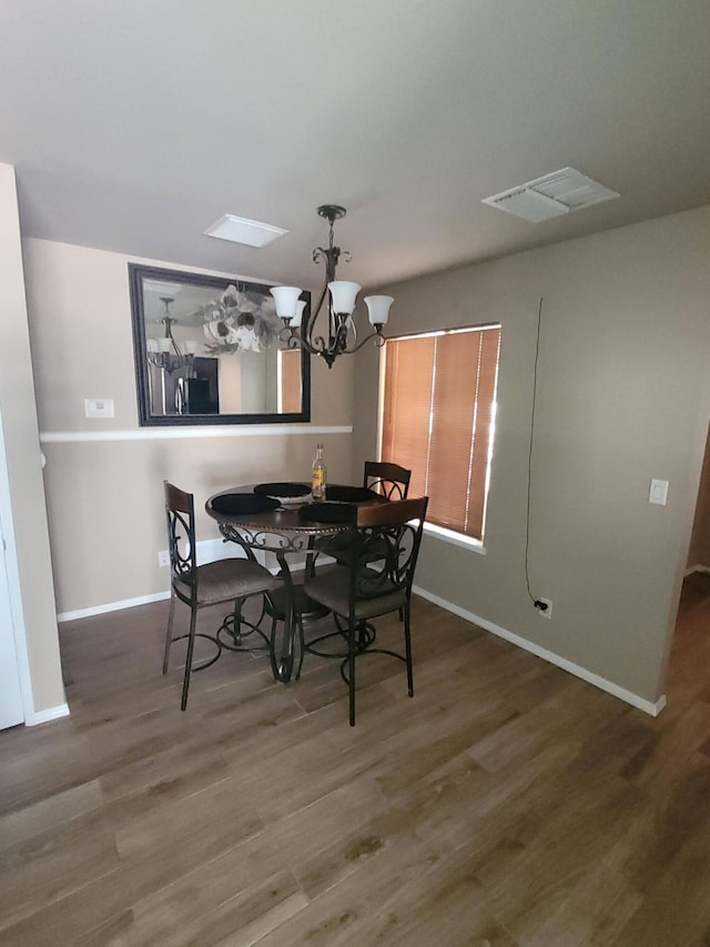 dining area with hardwood / wood-style floors and a notable chandelier