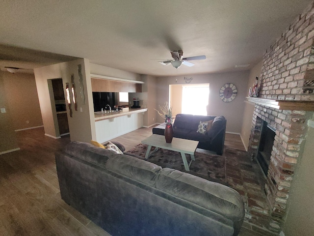 living room with sink, hardwood / wood-style flooring, a fireplace, and ceiling fan