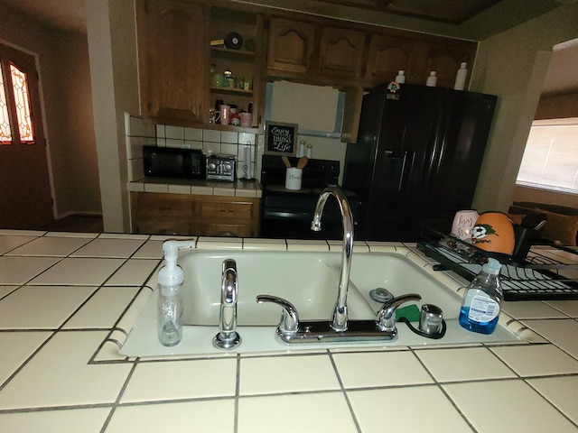 kitchen featuring tile counters, sink, decorative backsplash, and black appliances