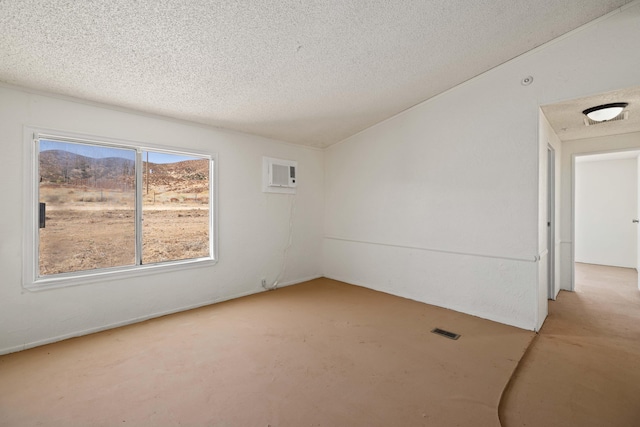 unfurnished room featuring an AC wall unit, a textured ceiling, and vaulted ceiling