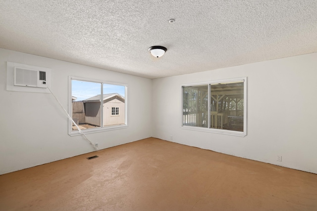 empty room with a textured ceiling and a wall unit AC