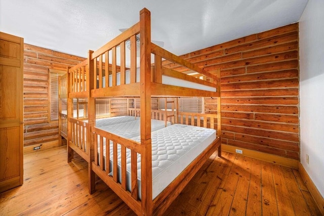 bedroom featuring log walls and light wood-type flooring