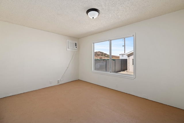 empty room with a textured ceiling and a wall unit AC