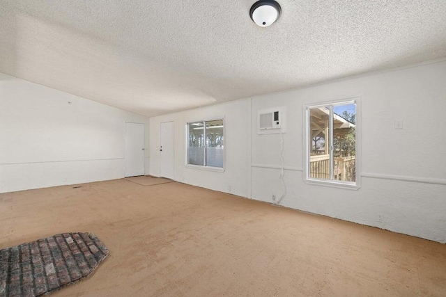 carpeted spare room with a textured ceiling and a wall unit AC