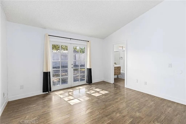 spare room with a textured ceiling, french doors, dark wood-type flooring, and lofted ceiling