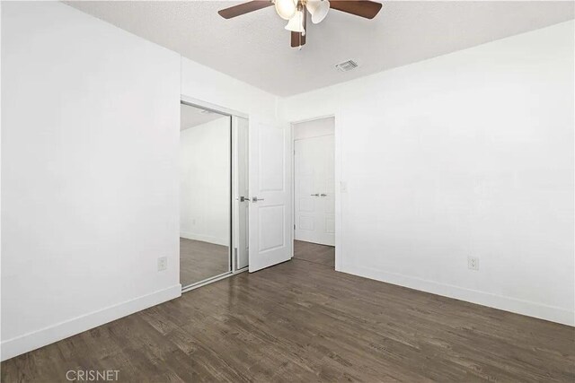 unfurnished bedroom featuring ceiling fan, dark wood-type flooring, and a closet