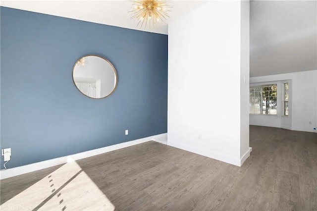 spare room featuring a chandelier and wood-type flooring