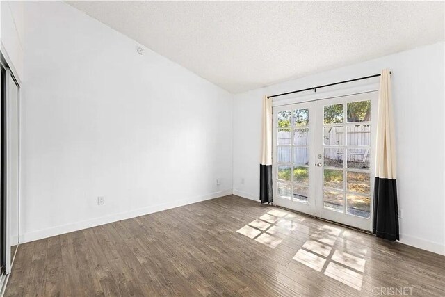 unfurnished room featuring hardwood / wood-style floors, a textured ceiling, french doors, and lofted ceiling