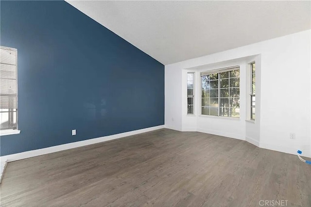 empty room with dark hardwood / wood-style flooring and vaulted ceiling