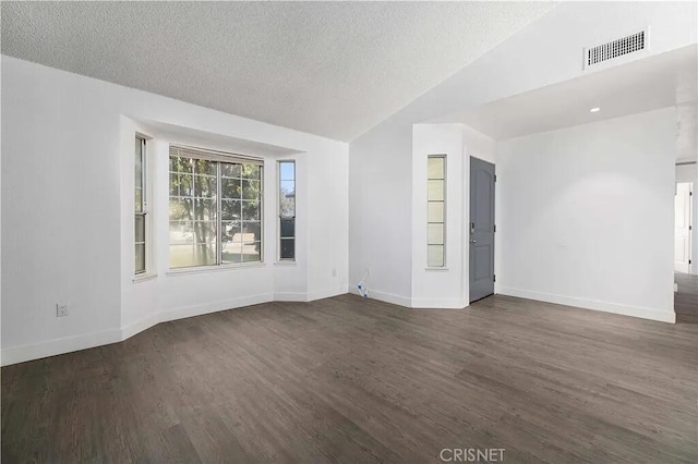 unfurnished room with lofted ceiling, a textured ceiling, and dark wood-type flooring