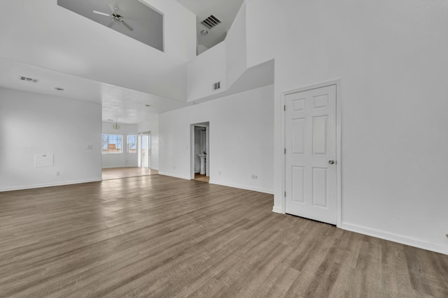 unfurnished living room with baseboards, ceiling fan, visible vents, and wood finished floors