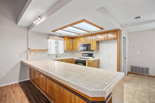 1086 Hickory Ave, Tehachapi, CA 93561 - kitchen featuring range with gas cooktop, black microwave, visible vents, and a sink