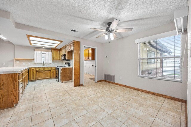 1086 Hickory Ave, Tehachapi, CA 93561 - kitchen with brown cabinetry, white electric stove, visible vents, and light countertops
