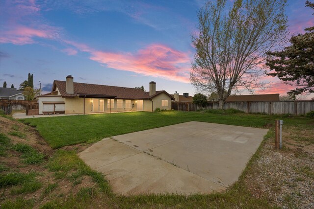1086 Hickory Ave, Tehachapi, CA 93561 - back of property at dusk with fence, a patio area, a yard, and stucco siding