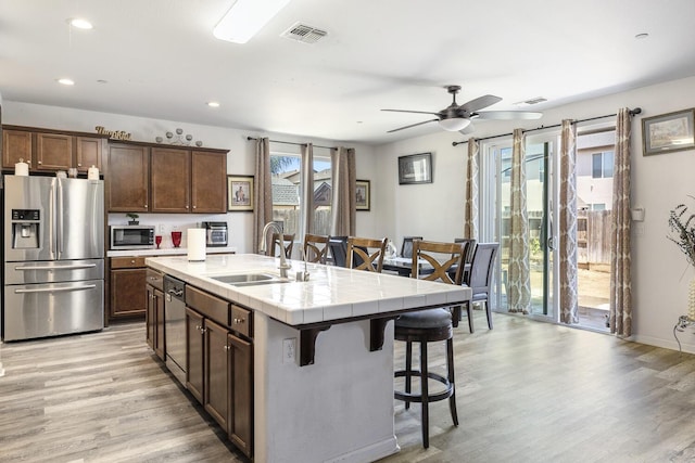 1413 La Quinta Way, Madera, CA 93638 - kitchen featuring stainless steel appliances, tile counters, a kitchen bar, light wood-style floors, and a ceiling fan