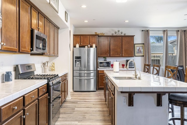 1413 La Quinta Way, Madera, CA 93638 - kitchen with appliances with stainless steel finishes, light wood finished floors, tile counters, a kitchen bar, and recessed lighting