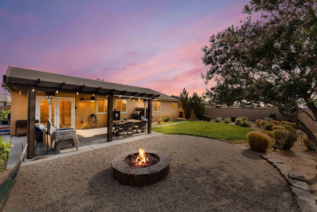 back house at dusk with a yard, a patio area, and a fire pit