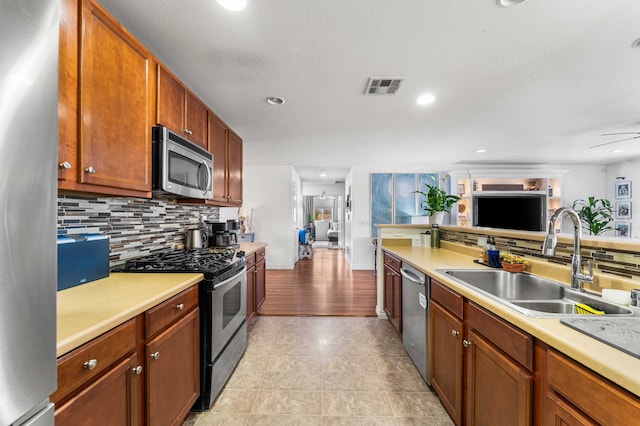 kitchen featuring appliances with stainless steel finishes, sink, decorative backsplash, light tile patterned floors, and ceiling fan