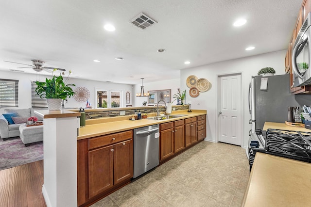 kitchen featuring sink, decorative light fixtures, kitchen peninsula, and appliances with stainless steel finishes