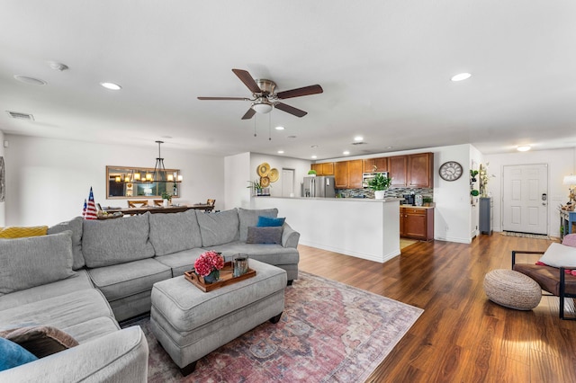 living room featuring dark wood-type flooring and ceiling fan with notable chandelier