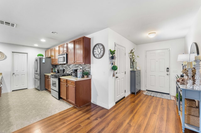 kitchen featuring backsplash, wood-type flooring, and appliances with stainless steel finishes