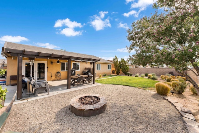 back of property with a lawn, a patio area, and a fire pit