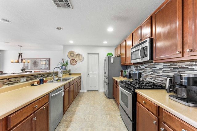 kitchen with appliances with stainless steel finishes, sink, backsplash, and decorative light fixtures