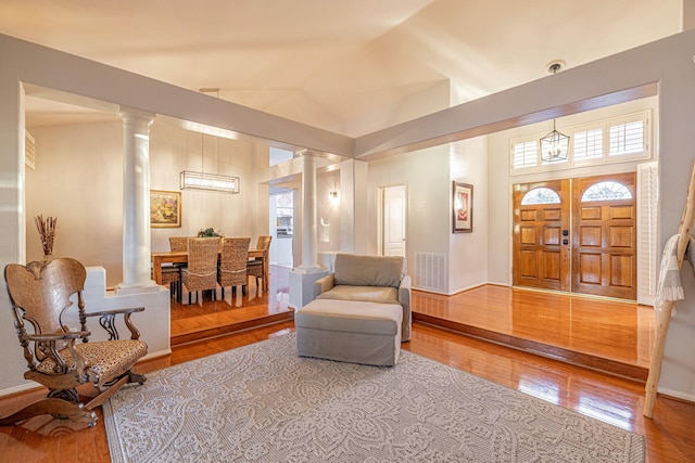 living area featuring decorative columns, wood finished floors, and a high ceiling