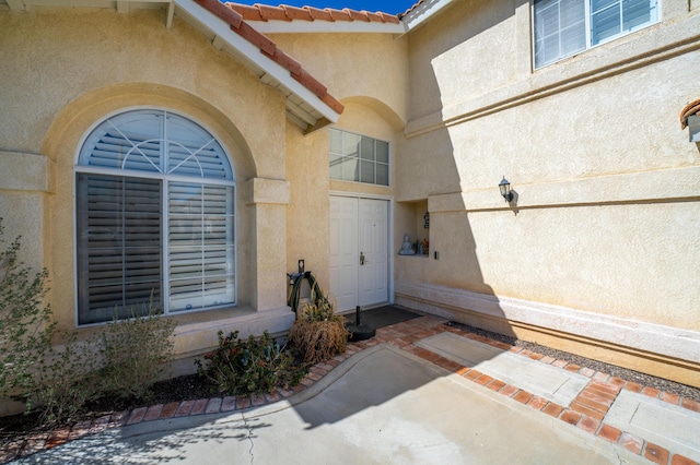 view of exterior entry featuring stucco siding and a tile roof