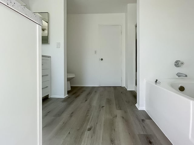 bathroom featuring a tub to relax in, vanity, hardwood / wood-style flooring, and toilet