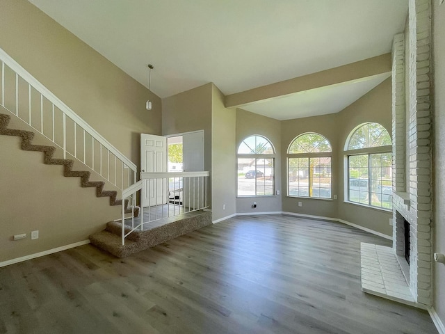 unfurnished living room with hardwood / wood-style flooring, a brick fireplace, and lofted ceiling