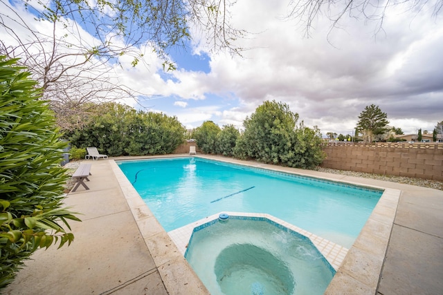 view of pool featuring a patio, fence, and a pool with connected hot tub