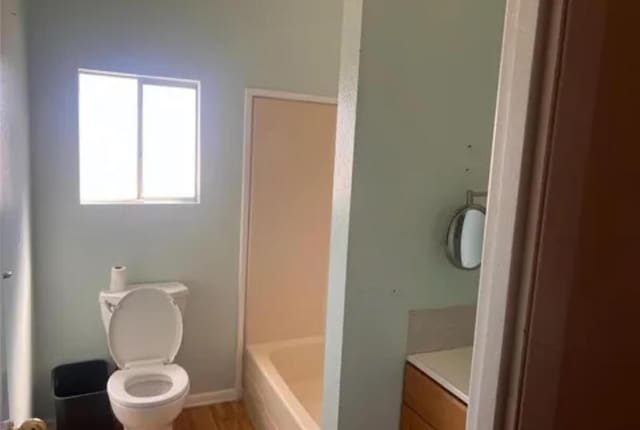 bathroom featuring vanity, hardwood / wood-style flooring, toilet, and a tub