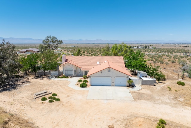 mediterranean / spanish house with a mountain view, a garage, concrete driveway, a tiled roof, and stucco siding