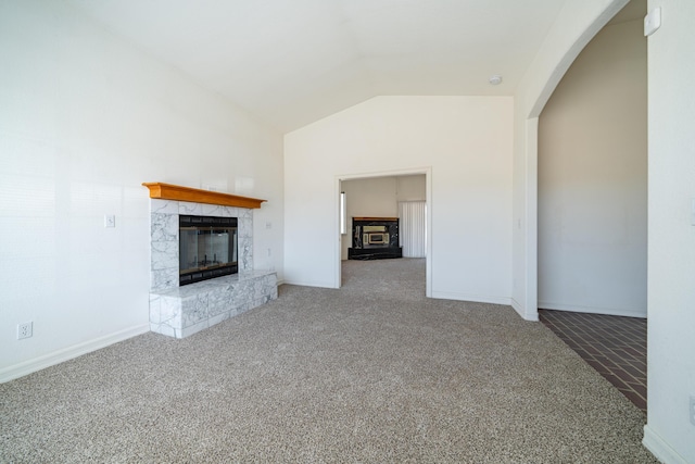 unfurnished living room with vaulted ceiling, a tiled fireplace, and carpet flooring