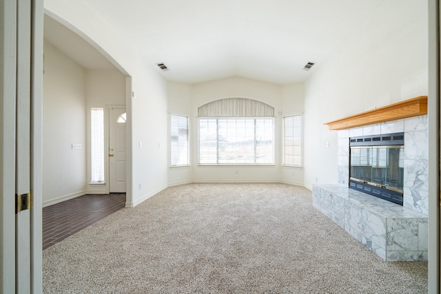 unfurnished living room with carpet floors, a tile fireplace, visible vents, and baseboards