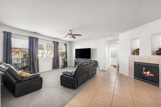 living room featuring light tile patterned floors, a tile fireplace, and ceiling fan