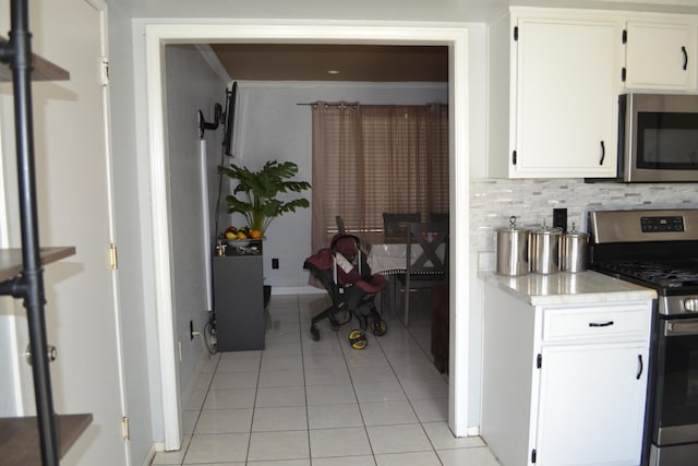 kitchen with backsplash, white cabinets, light tile patterned flooring, and appliances with stainless steel finishes