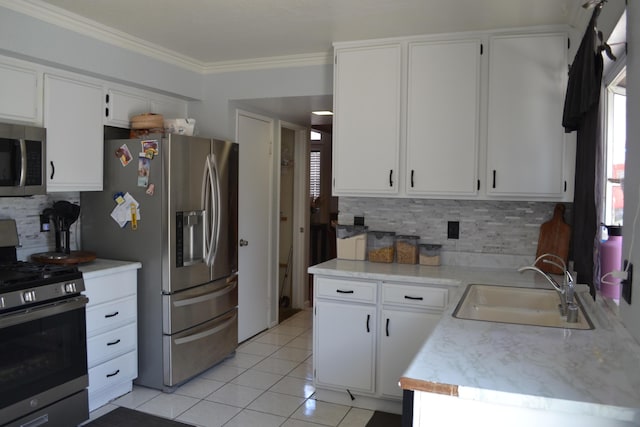 kitchen with backsplash, stainless steel appliances, sink, light tile patterned floors, and white cabinetry