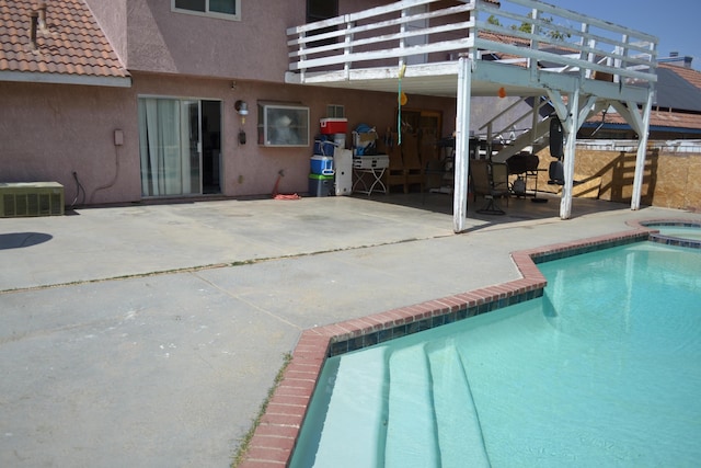 view of swimming pool featuring central air condition unit, an in ground hot tub, and a patio