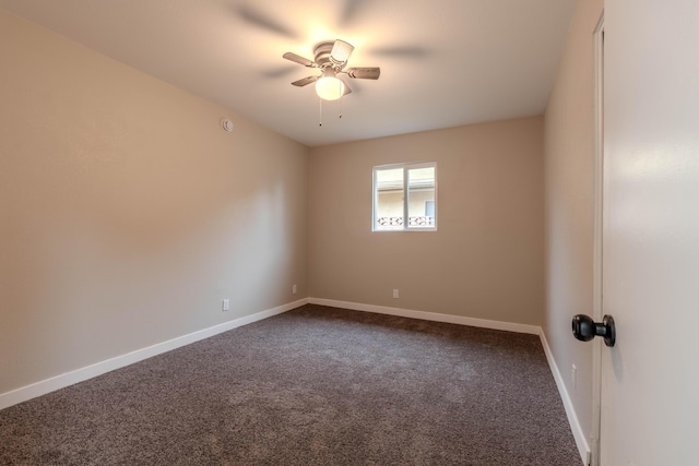 unfurnished room featuring baseboards, dark carpet, and ceiling fan