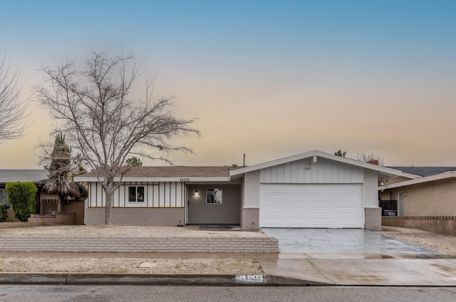 view of front of home with concrete driveway, brick siding, and an attached garage