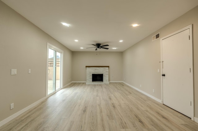 unfurnished living room featuring light wood-style flooring, a premium fireplace, visible vents, and baseboards