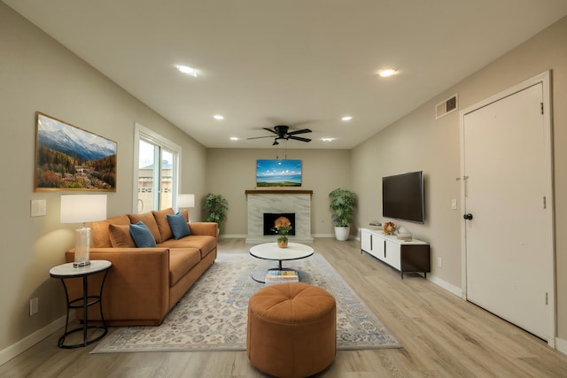 living room featuring light wood-style flooring, recessed lighting, a premium fireplace, visible vents, and baseboards