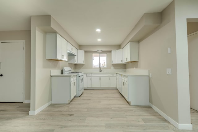 kitchen featuring light wood finished floors, white gas range oven, and baseboards