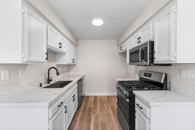 43441 W 30th St Unit 3, Lancaster, CA 93536 - kitchen with appliances with stainless steel finishes, white cabinetry, light wood-style flooring, and light stone countertops